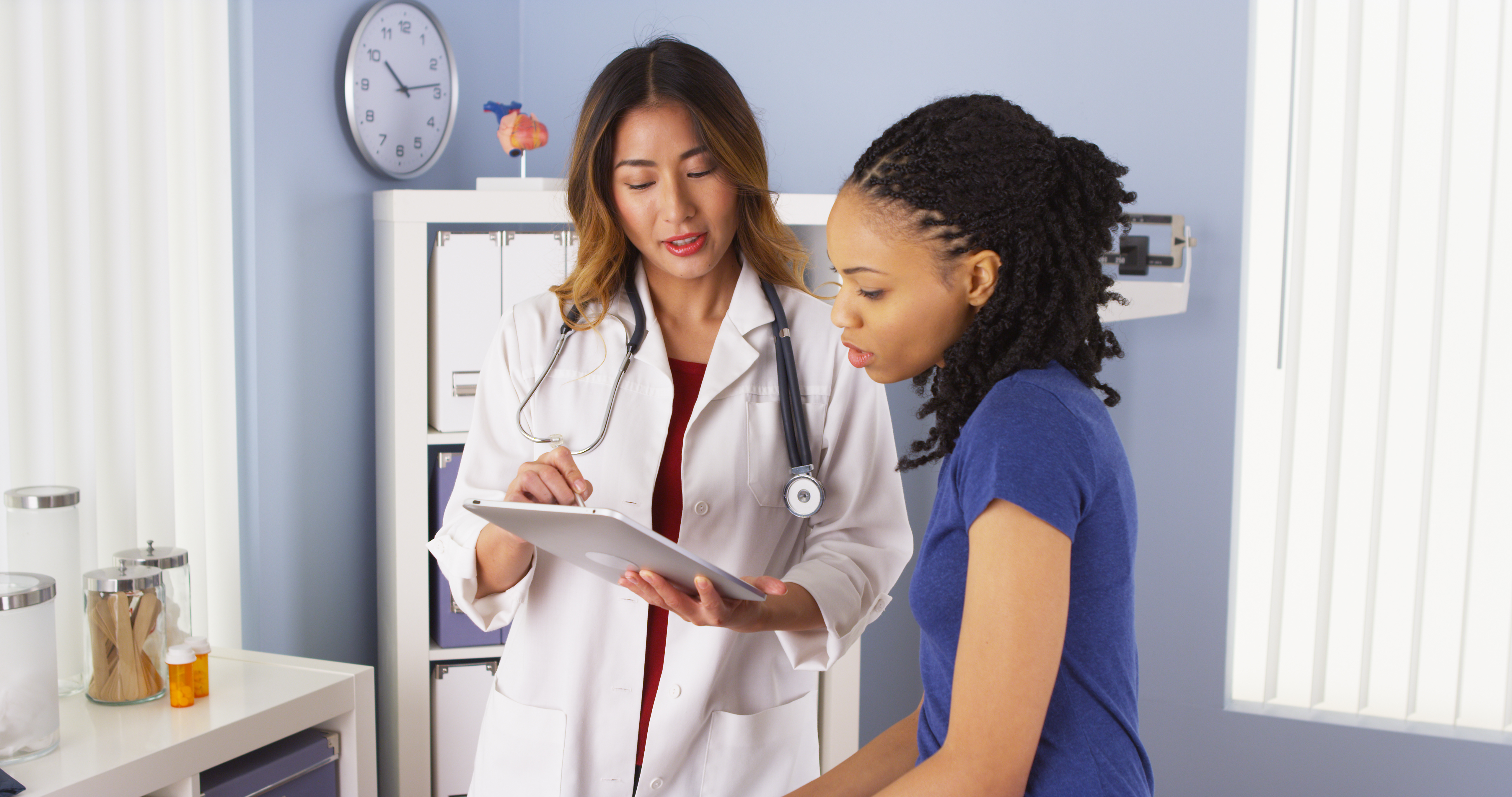 Asian doctor reviewing tablet with black female patient