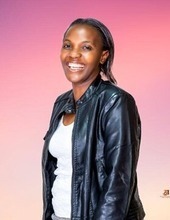 Black woman in leather jacket smiling, pink background