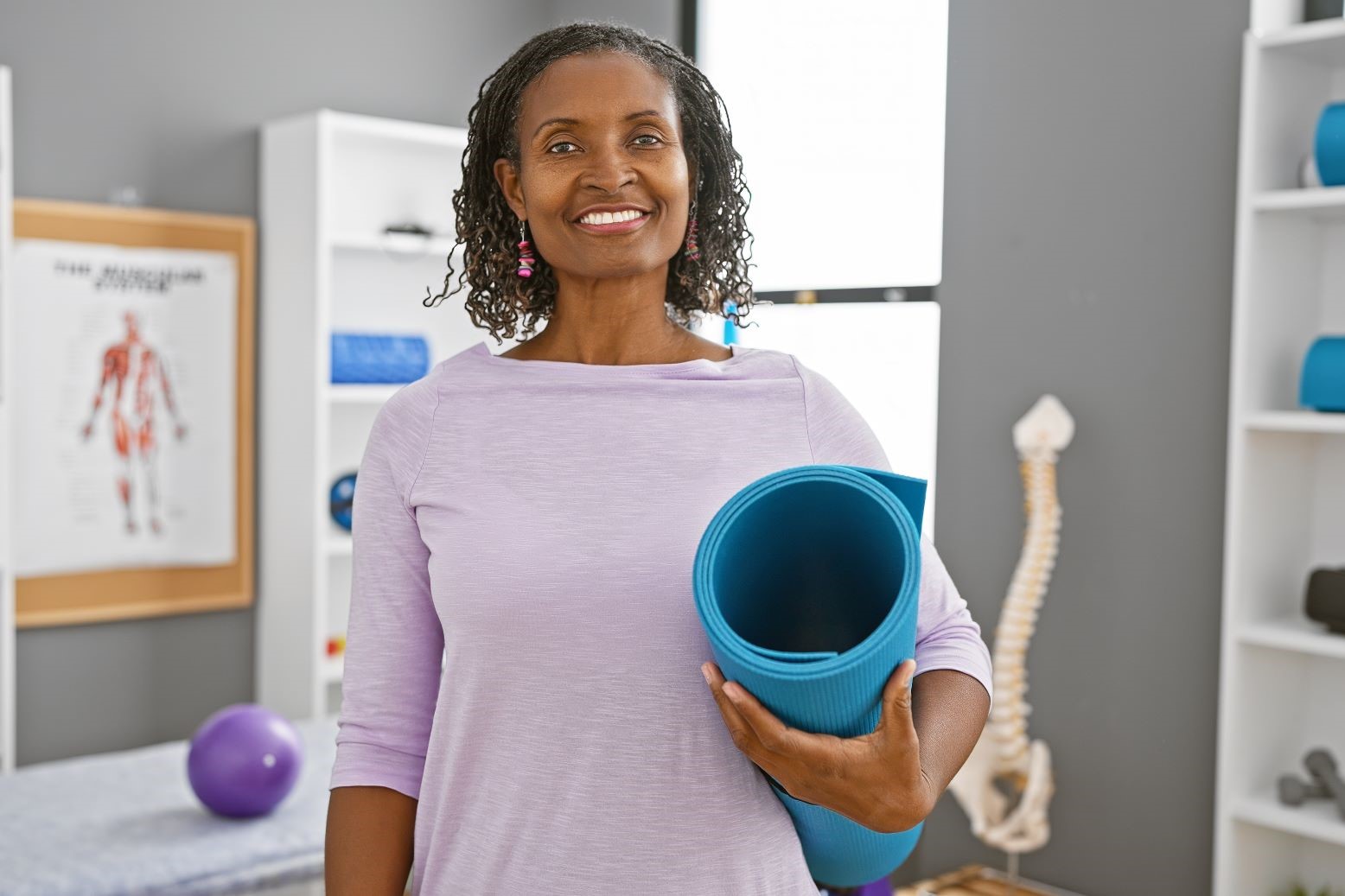 woman holding yoga mat in rehabilitation clinic