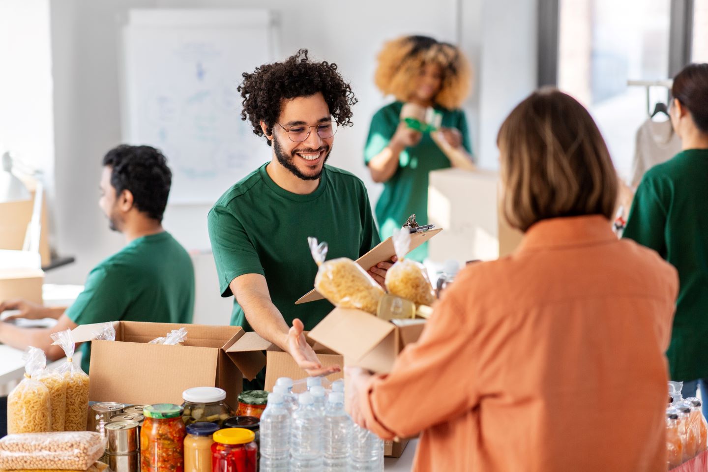 A male nonprofit leader helping a woman gather food at a distribution facility.