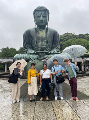Students pose in front of a Buddha statue.